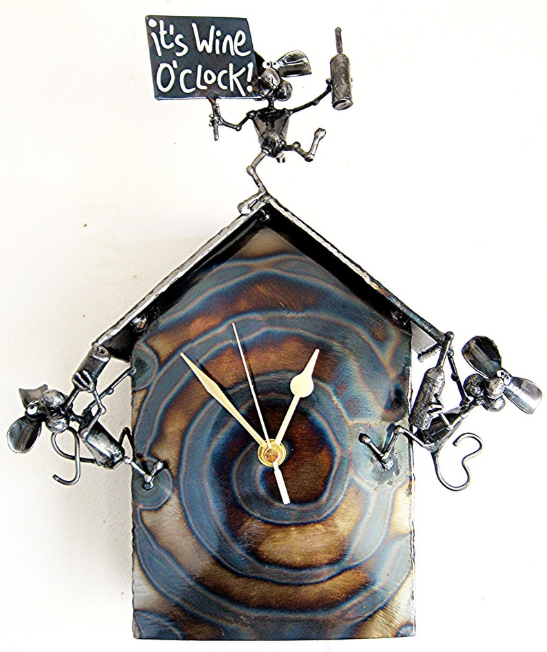 May include: A metal wall clock with a whimsical design featuring a mouse holding a bottle of wine and a sign that reads "It's Wine O'Clock!" The clock face is a circular, swirling pattern of blue and brown metal.