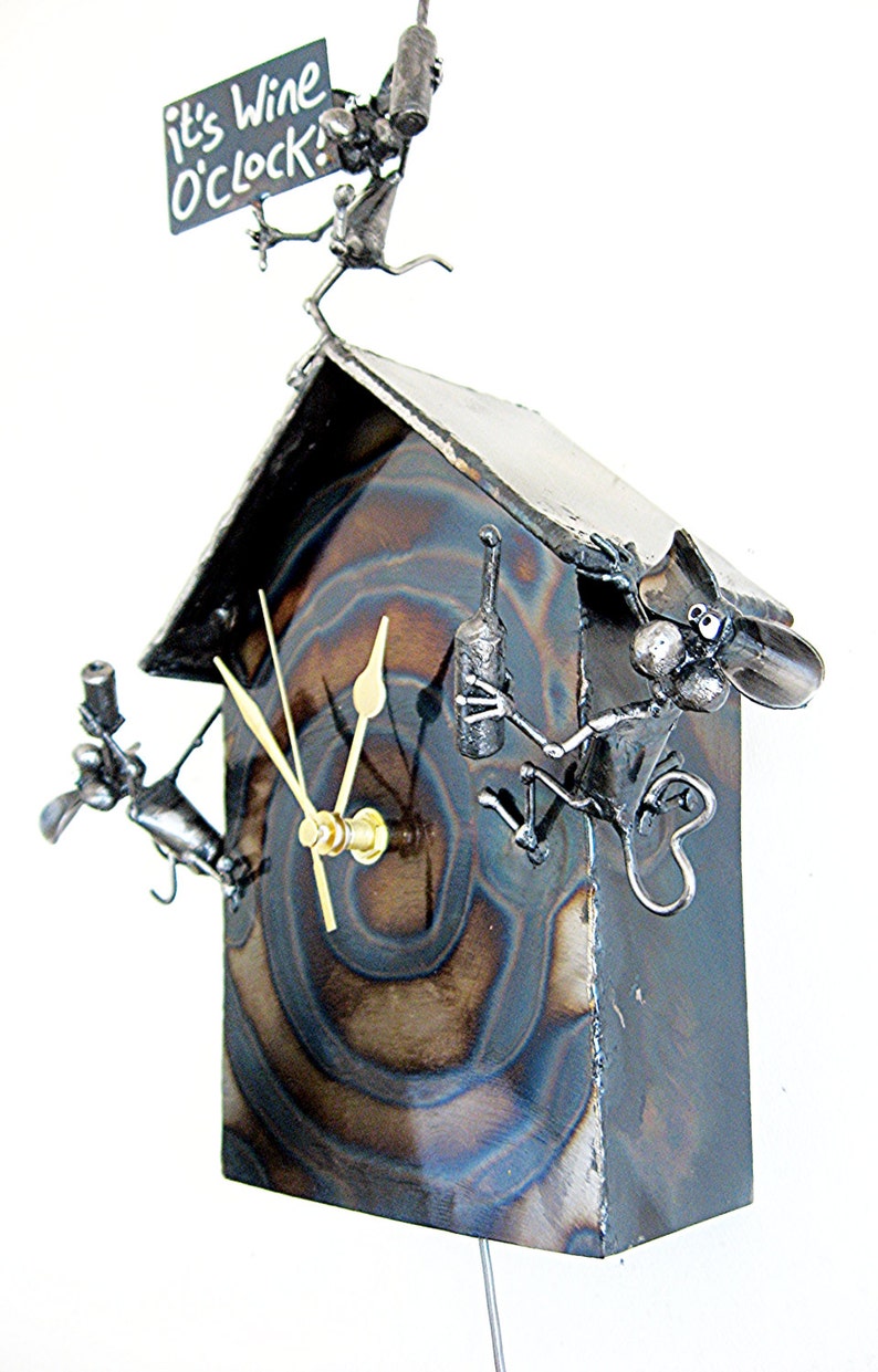 May include: A metal clock shaped like a house with a sign that says "it's wine o'clock!" and three mice figures holding wine bottles. The clock face has a swirling pattern and gold hands.