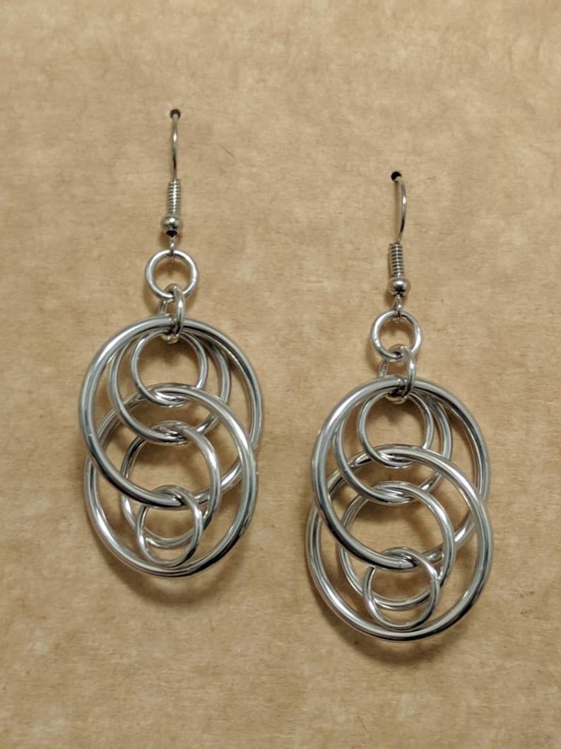 May include: Silver earrings with a design of interlocking circles.