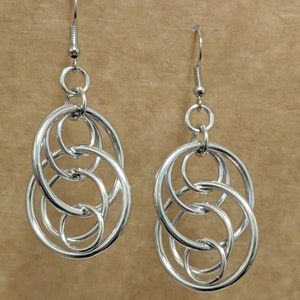 May include: Silver dangle earrings with multiple interlocking circles.