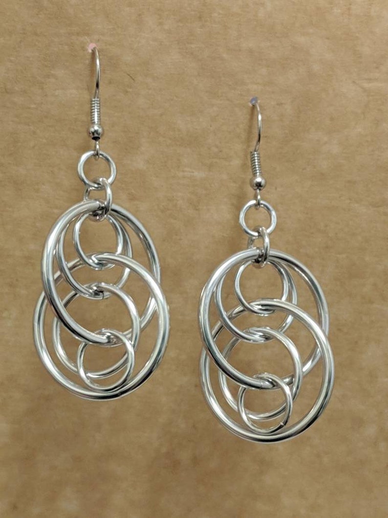 May include: Silver dangle earrings with multiple interlocking circles.
