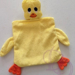 Puede incluir: Un juguete de peluche amarillo en forma de patito con patas naranjas. El patito tiene ojos bordados y un pico.
