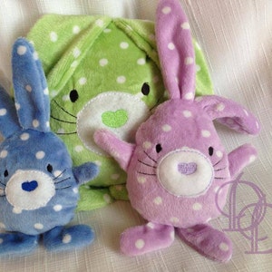May include: Three plush bunny toys. One is green with white polka dots, one is blue with white polka dots, and one is purple with white polka dots.