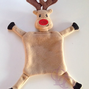 Puede incluir: Un reno de peluche marrón con la nariz roja y cuernos marrones. El reno está tumbado de espaldas con las piernas y los brazos extendidos.