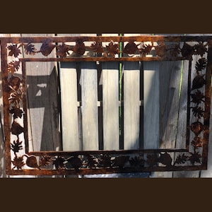 Może przedstawiać: Rustykalna metalowa rama z wyciętym wzorem liści i żołędzi. Rama jest pomalowana na brązowo z efektem postarzenia.