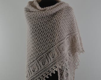 May include: A light beige knitted shawl with a detailed openwork pattern. The shawl is draped over a mannequin, showcasing its triangular shape and intricate lace border. The colour is a soft neutral, suitable for various outfits.