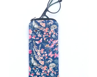 May include: A blue zippered glasses case with a floral pattern featuring pink flowers, birds, squirrels, and hedgehogs.