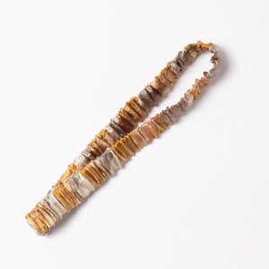 May include: A brown and beige elastic headband with a gathered, ruffled texture.
