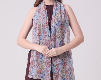 May include: A sheer scarf with a colorful coral reef pattern in shades of blue, red, and green. The scarf is draped over a dark burgundy dress. The scarf is lightweight and appears to be made of a delicate fabric.