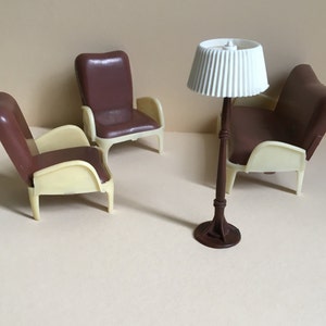 May include: Three brown plastic chairs and a white lamp with a brown base. The chairs have a cream colored bottom and are arranged on a beige surface.