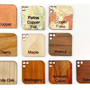 May include: A selection of wood and metal samples with rounded corners, each labelled with its material. Materials include copper, copper flake, cherry, maple, walnut, white oak, mahogany, aromatic cedar, and sapele.