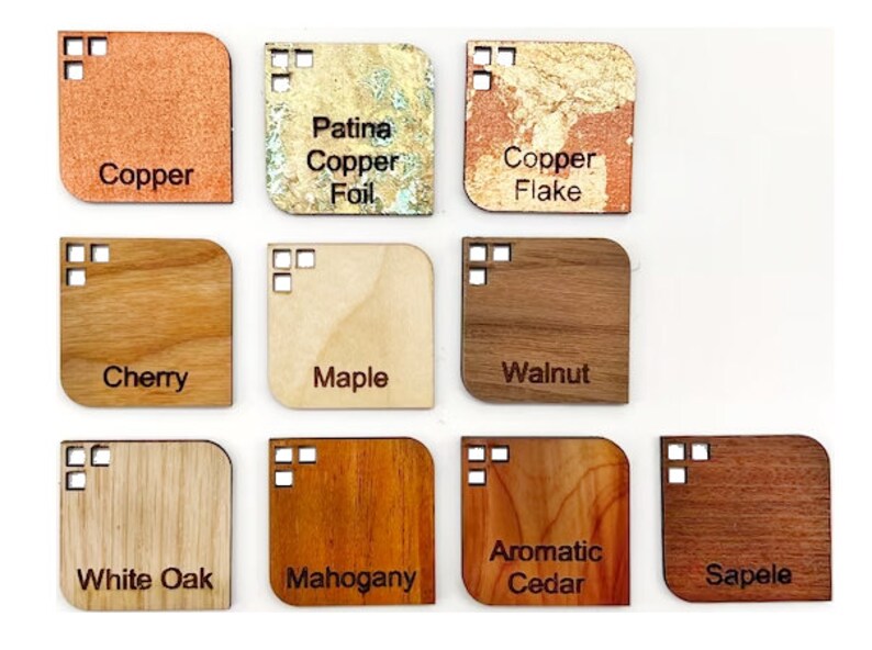 May include: A selection of wood and metal samples with rounded corners, each labelled with its material. Materials include copper, copper flake, cherry, maple, walnut, white oak, mahogany, aromatic cedar, and sapele.