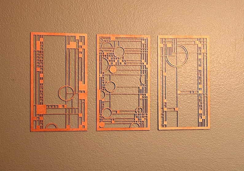 May include: Three geometric wall art pieces in a light orange color. Each piece features a different design with a repeating pattern of squares and circles.