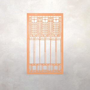 May include: A laser-cut, orange-colored paper craft featuring a geometric design reminiscent of architectural stained glass. The design includes rectangular and square shapes, with intricate patterns and three small holes at the top.