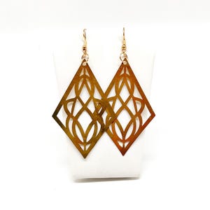 May include: A pair of gold-toned earrings with a geometric diamond shape and intricate cut-out designs.