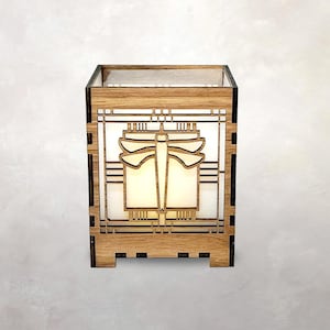 May include: A wooden lantern featuring a dragonfly design. The lantern is crafted from light-coloured wood, showcasing a geometric pattern and a dragonfly silhouette. The interior emits a soft light, creating a warm atmosphere.