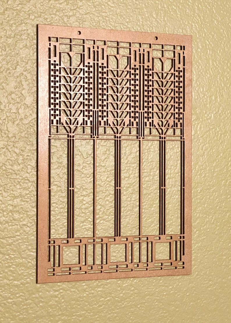 May include: A copper-colored, rectangular decorative panel with an intricate geometric design. The panel features a series of vertical and horizontal lines, creating a repeating pattern of squares, rectangles, and stylized floral motifs. Two small holes are at the top for hanging.