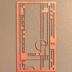 May include: A geometric design cut out of wood with a reddish-brown color. The design features a circle, squares, and rectangles.