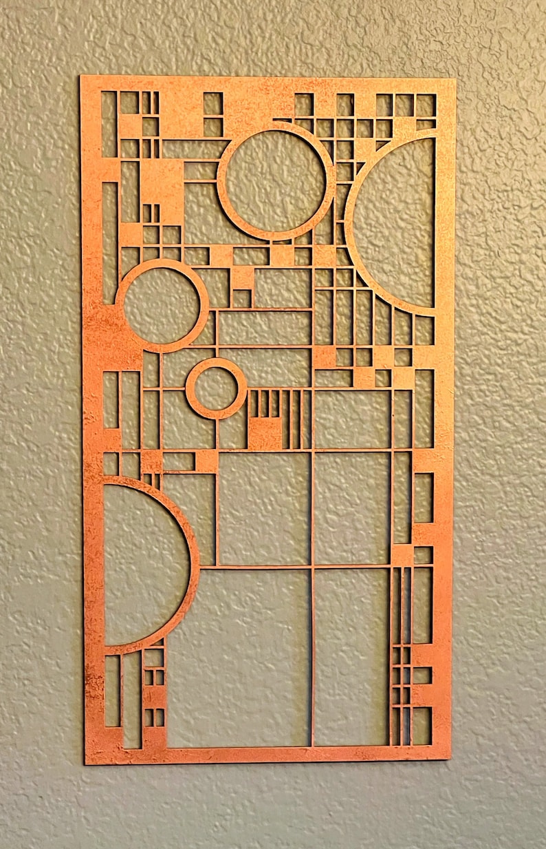 Op de afbeelding: Een koperkleurig metalen wandkunstwerk met een geometrisch ontwerp met vierkanten, rechthoeken en cirkels. Het ontwerp doet denken aan de Art Deco-stijl.