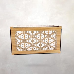 May include: A rectangular wooden box featuring a laser-cut front panel with a repeating geometric star pattern. The light-colored wood grain is visible on the frame, while the intricate cutouts create a lattice design across the front surface.