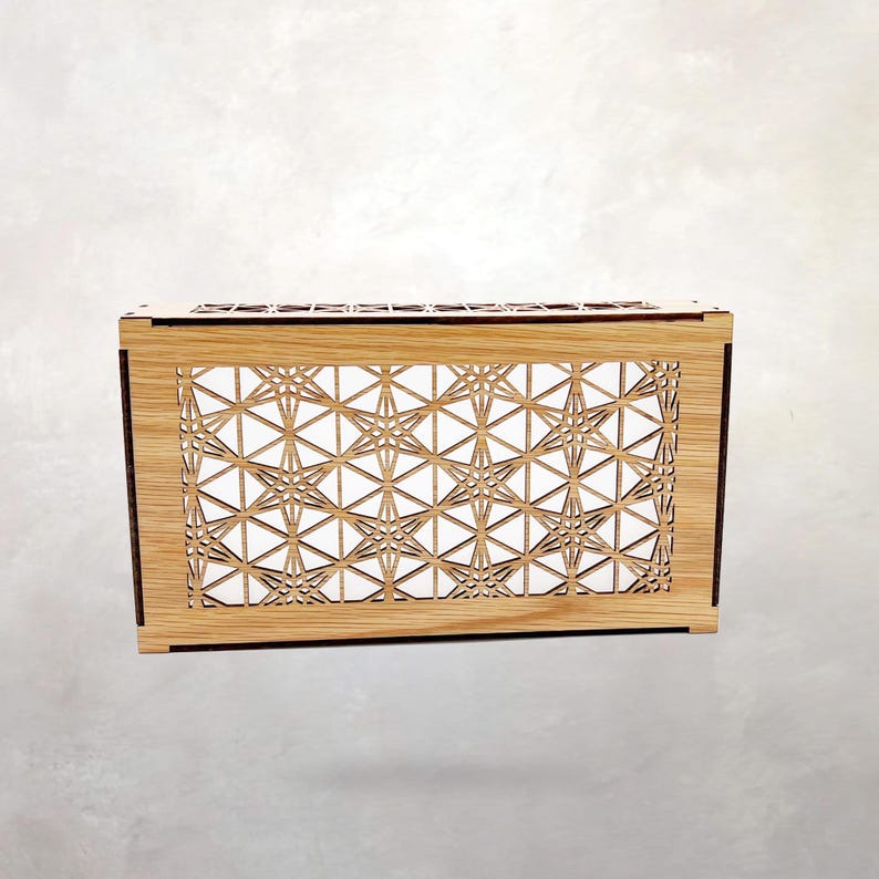 May include: A rectangular wooden box featuring a laser-cut front panel with a repeating geometric star pattern. The light-colored wood grain is visible on the frame, while the intricate cutouts create a lattice design across the front surface.