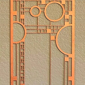 May include: A copper-colored metal wall art piece with a geometric design featuring squares, rectangles, and circles. The design is reminiscent of the Art Deco style.