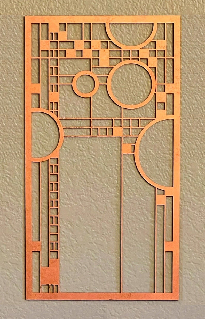 May include: A copper-colored metal wall art piece with a geometric design featuring squares, rectangles, and circles. The design is reminiscent of the Art Deco style.