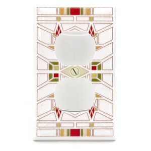 May include: A white electrical outlet cover with a geometric design in red, green, and gold. The cover features two white, oval-shaped outlets and a gold screw in the center. The design is reminiscent of stained glass.