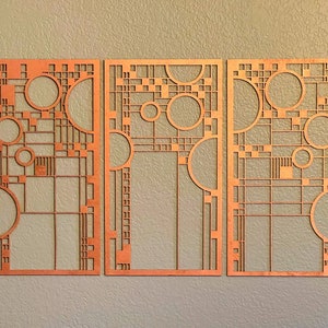 Op de afbeelding: Drie houten wandpanelen met geometrische ontwerpen met cirkels en vierkanten. De panelen zijn lichtbruin van kleur en hebben een verweerde afwerking.