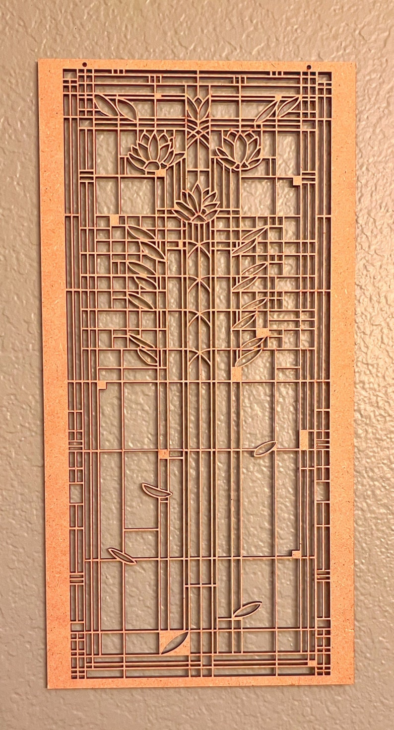 May include: A laser-cut wooden wall art piece featuring a floral and geometric design. The artwork is a rectangular shape with a light brown color. The design includes stylized flowers, leaves, and a grid-like pattern.
