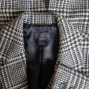 Puede incluir: Primer plano de una blazer con estampado de pata de gallo en blanco y negro. La blazer tiene un forro de sat&eacute;n negro y una etiqueta Pendleton. La blazer tiene dos botones y solapas con muescas. La tela es lana tejida.