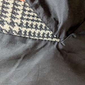 Puede incluir: Primer plano de una secci&oacute;n de tela que muestra un patr&oacute;n de pata de gallo en blanco y negro, con un forro negro. El forro es un material negro liso y liso. Las dos telas est&aacute;n cosidas juntas.