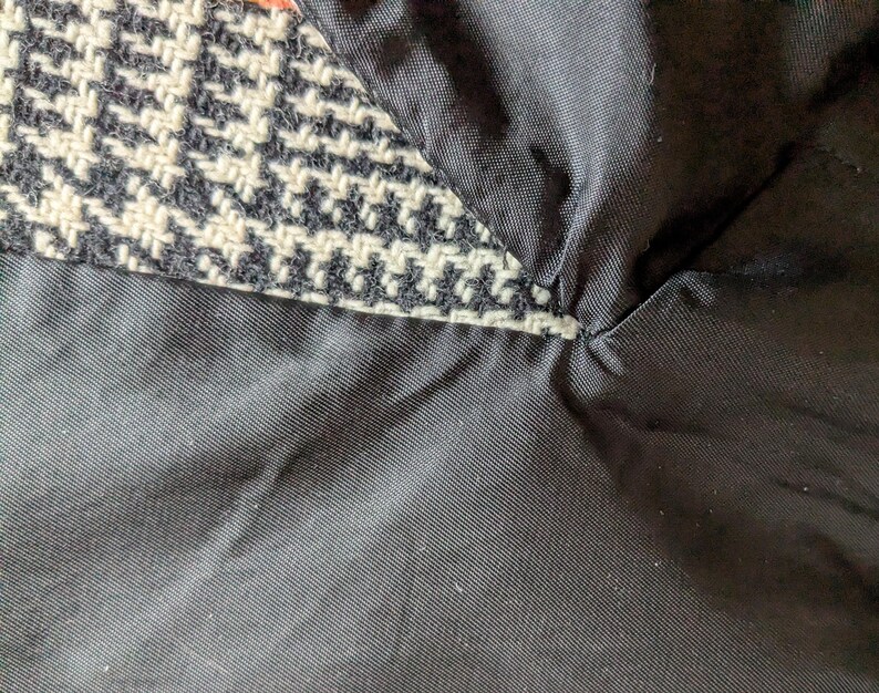 Puede incluir: Primer plano de una secci&oacute;n de tela que muestra un patr&oacute;n de pata de gallo en blanco y negro, con un forro negro. El forro es un material negro liso y liso. Las dos telas est&aacute;n cosidas juntas.