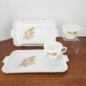 Peut inclure: Un ensemble de service blanc vintage avec deux plateaux rectangulaires et deux tasses à thé. Chaque pièce présente un motif d'épi de blé doré et un bord perlé. Les tasses à thé sont sur un support transparent. Les plateaux mesurent environ 25 cm de long.