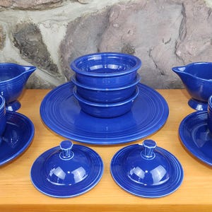 May include: A set of blue ceramic dishes, including a serving platter, two creamer pitchers, two teacups and saucers, and two covered butter dishes.