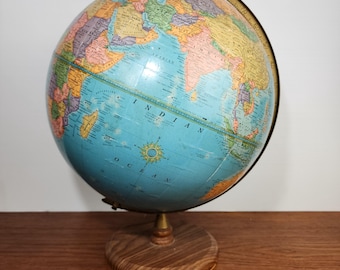 May include: A vintage globe with a blue and yellow map of the world. The globe is on a wooden stand with a brass meridian.