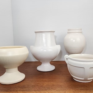 Peut inclure: Quatre pots en céramique blanche de différentes tailles et formes. Les pots sont tous de style minimaliste avec des bords lisses et arrondis.