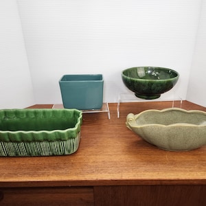 May include: Four green ceramic planters, two are rectangular, one is a bowl, and one is a long oval shape with handles.