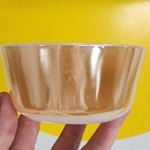 May include: A clear glass bowl with a gold iridescent finish. The bowl has a rounded shape and a smooth, reflective surface.