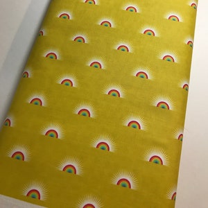 May include: Yellow fabric with a repeating pattern of white sunbursts with rainbow arches.