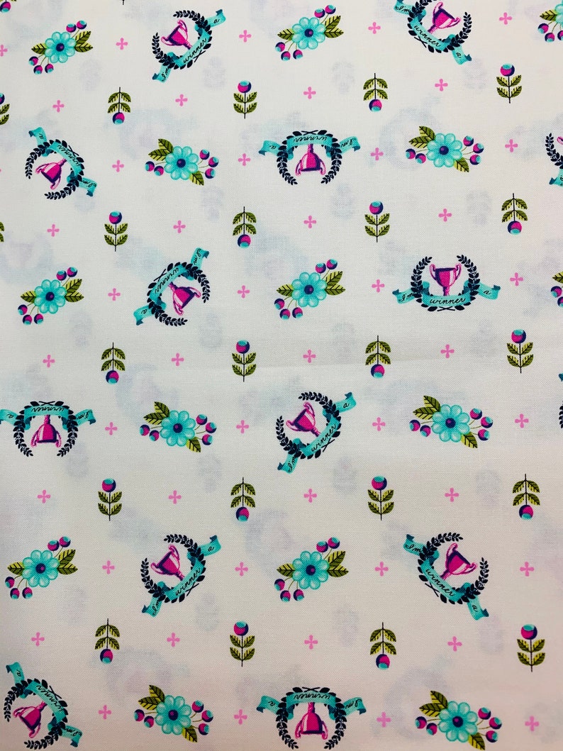 May include: White fabric with a repeating pattern of blue and pink floral designs, green leaves, and a trophy with the text "I'm a winner" on a blue ribbon.