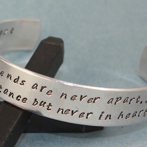 May include: Silver bracelet with the inscription "True Friends are never apart...  never in heart" with a small heart symbol.