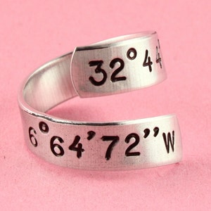 May include: A silver ring with the coordinates "32° 44' 64' 72" W" engraved on it.