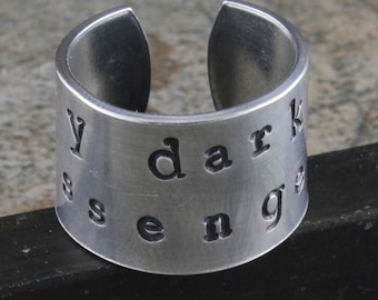 May include: A silver ring with the words "My dark sense" engraved on it.