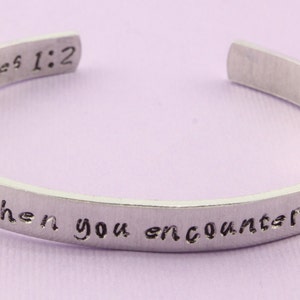 May include: Silver bracelet with the text "The joy when you encounter affliction" and "James 1:2" engraved on it.