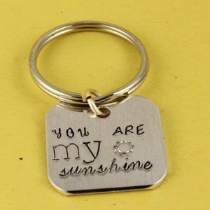 May include: Silver keychain with a square tag that reads "You are my sunshine" with a small sun graphic.