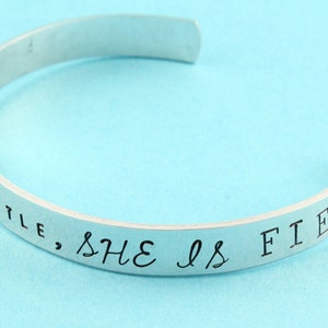 Peut inclure: Bracelet en argent avec l'inscription "She is fierce, little" grav&eacute;e sur la bande.