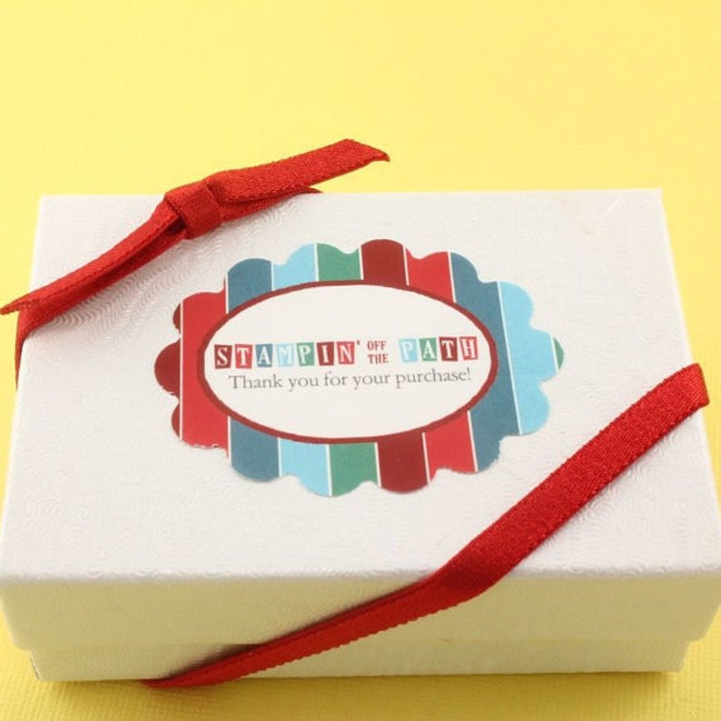 Peut inclure: Bo&icirc;te cadeau blanche avec un ruban rouge nou&eacute; autour. La bo&icirc;te a un autocollant avec le texte "Stampin' Off the Path" et "Merci pour votre achat !"
