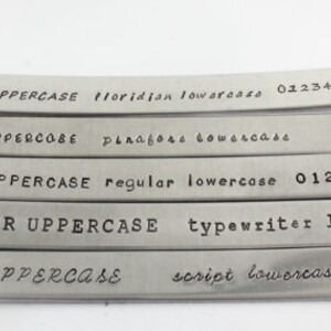 Peut inclure: Cinq bandes m&eacute;talliques avec diff&eacute;rents styles et tailles de police. Le texte sur les bandes est le suivant&nbsp;: FLORIDIAN UPPERCASE floridian lowercase 0123456789, PINGFORE UPPERCASE pinagore lowercase, REGULAR UPPERCASE regular lowercase 0123456789, TYPEWRITER UPPERCASE typewriter lowercase, SCRIPT UPPERCASE script lowercase.