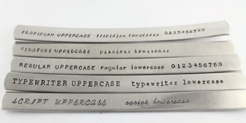 Peut inclure: Cinq bandes m&eacute;talliques avec diff&eacute;rents styles et tailles de police. Le texte sur les bandes est le suivant&nbsp;: FLORIDIAN UPPERCASE floridian lowercase 0123456789, PINGFORE UPPERCASE pinagore lowercase, REGULAR UPPERCASE regular lowercase 0123456789, TYPEWRITER UPPERCASE typewriter lowercase, SCRIPT UPPERCASE script lowercase.